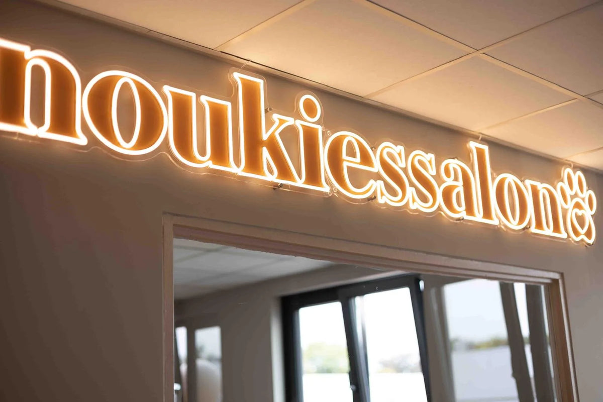 Neonletters met de naam noukiessalon boven de doorgang